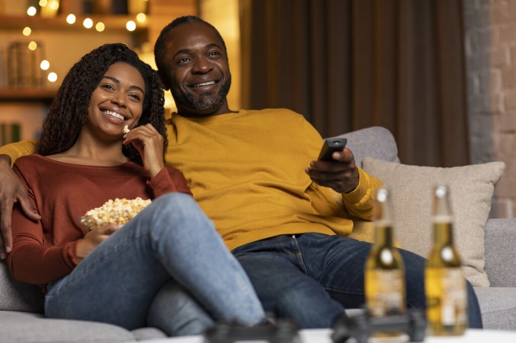 Portrait of happy relaxed black spouses watching movie at home